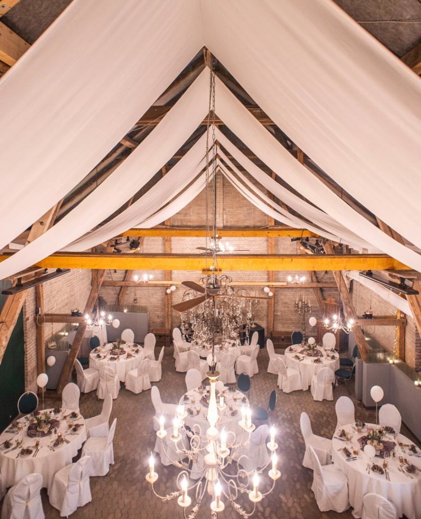 Stühle und Tische in Weiß verkleidet, Dekoration mit Blumen, Kerzen und weißen Luftballons