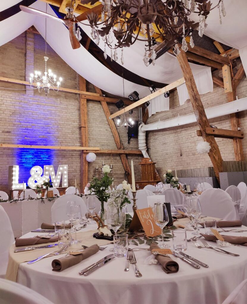 Hochzeit Scheune, Stühle und Tische in Weiß verkleidet mit weiße Stoffservietten und Blumen