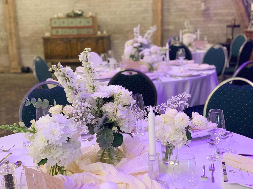 Stühle und Tische in Weiß verkleidet, Dekoration mit Blumen, Luftballons und Tischnamen aus Holz