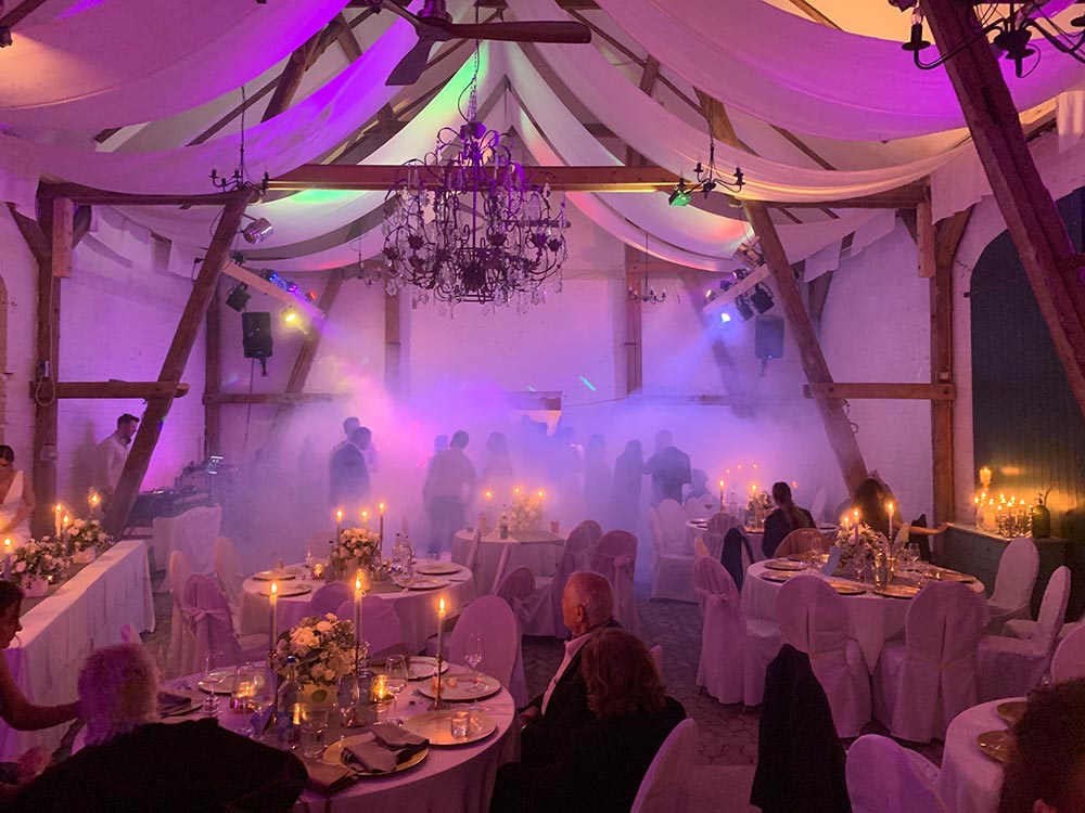 Stühle und Tische in Weiß verkleidet, Dekoration mit Blumen, Kerzen und farbigen Lichteffekte