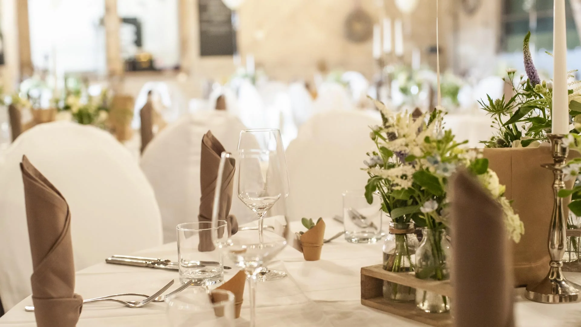 Stühle und Tische in Weiß verkleidet, Dekoration mit Blumen, Kerzen sowie weißen Luftballons